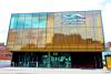 Photographie en couleur d’un édifice à trois étages, avec une devanture en verre. Il porte l'inscription La Nouvelle Scène -Gilles Desjardins-.