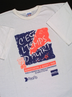 Photograph of a white T-shirt with the words, in blue and bright orange: “C’est l’temps d’agir !” (It’s time to act!). The purpose of the demonstration and the logos of two organizations are also printed on the T-shirt.